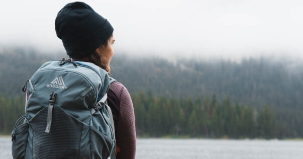 Woman with camping backpack looking out over water